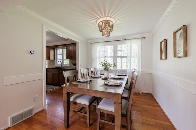 dining room featuring a chandelier, ornamental molding, wood finished floors, and baseboards
