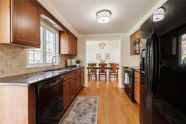 kitchen featuring black appliances, a sink, light wood-style flooring, decorative backsplash, and ornamental molding