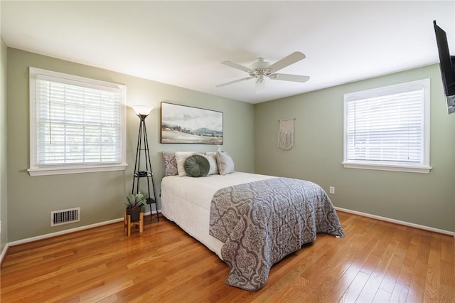 bedroom featuring light wood-style flooring, multiple windows, baseboards, and ceiling fan