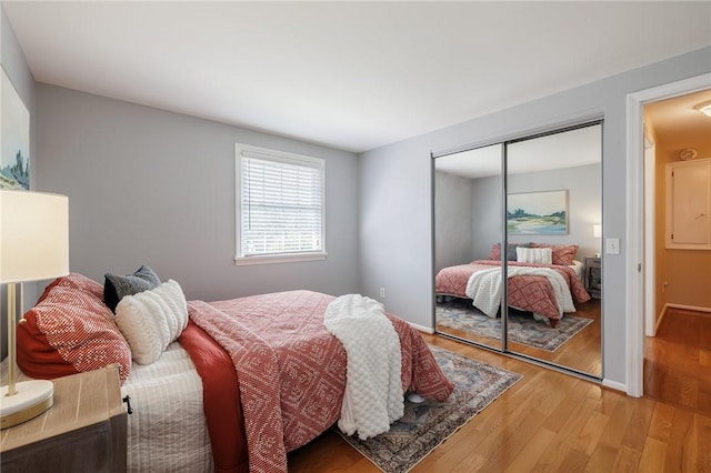 bedroom with light wood-style floors, a closet, and baseboards