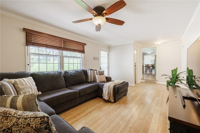 living room with a ceiling fan, crown molding, light wood finished floors, and baseboards