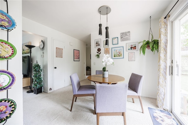 dining space featuring light carpet and baseboards