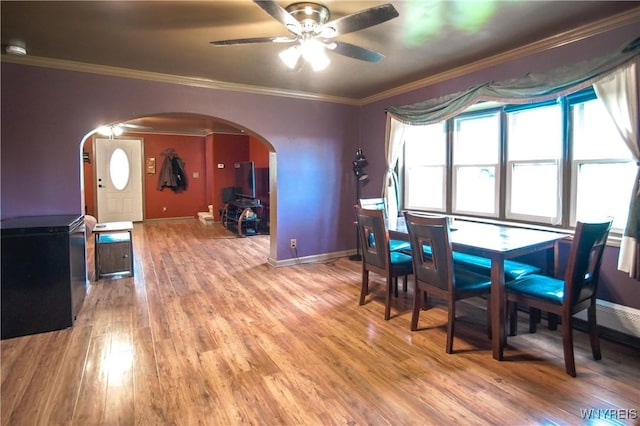 1934 E Middle Rd, Sheridan, NY 14136 - dining room featuring arched walkways, light wood-type flooring, ceiling fan, baseboards, and crown molding