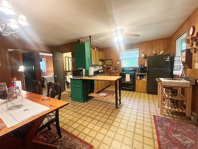 920 New Kingston Rd, Middletown, NY 12455 - kitchen with green cabinets, black appliances, wooden walls, light flooring, and a ceiling fan