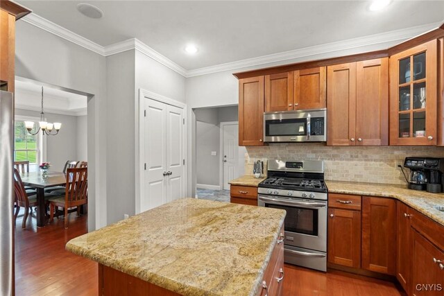 3543 Lost Hollow Rd, Skaneateles, NY 13152 - kitchen with appliances with stainless steel finishes, ornamental molding, brown cabinets, backsplash, and light stone counters