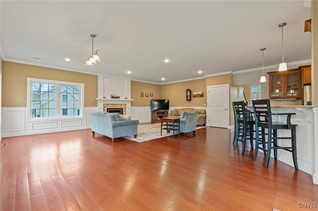 3543 Lost Hollow Rd, Skaneateles, NY 13152 - living area featuring ornamental molding, wood finished floors, a stone fireplace, wainscoting, and recessed lighting