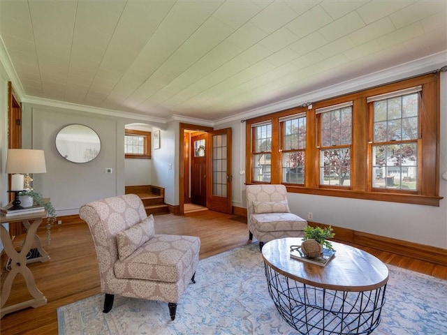 living room featuring crown molding, baseboards, wood finished floors, and arched walkways