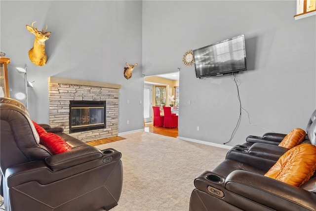 carpeted living room featuring baseboards, a fireplace, and a towering ceiling