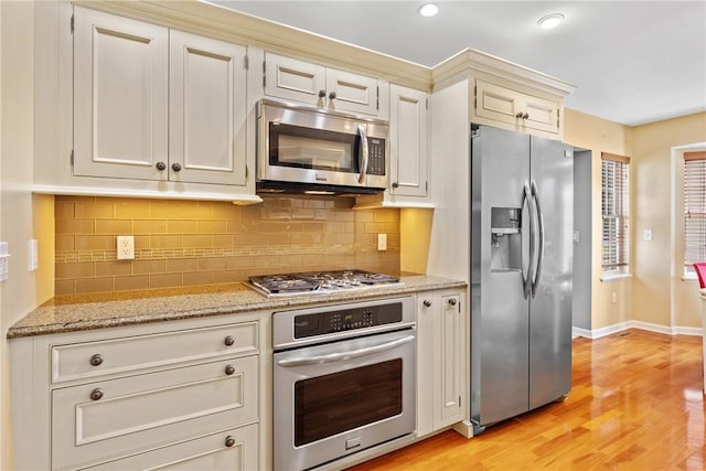 kitchen featuring stainless steel appliances, light wood-style floors, tasteful backsplash, baseboards, and recessed lighting