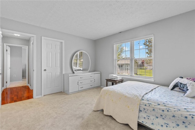bedroom featuring light colored carpet and a textured ceiling