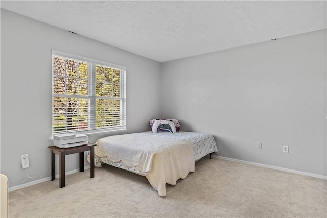 bedroom featuring light colored carpet, a textured ceiling, and baseboards