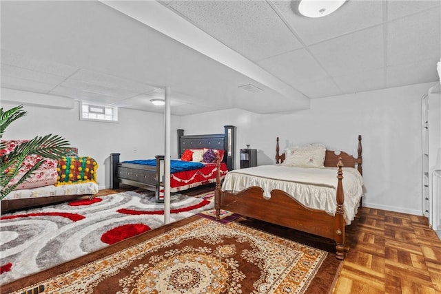 bedroom with a paneled ceiling and baseboards
