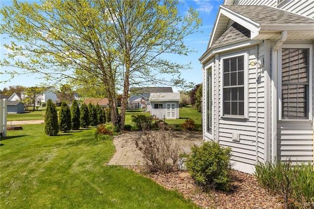 view of property exterior featuring a yard, an outbuilding, and a shingled roof