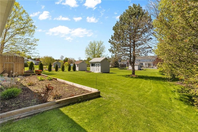view of grassy yard featuring a residential view, a shed, and an outbuilding