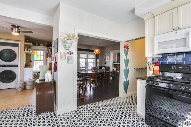 82 Radcliffe Rd, Buffalo, NY 14214 - kitchen with estacked washer and dryer, white microwave, black gas range, ceiling fan, and baseboards