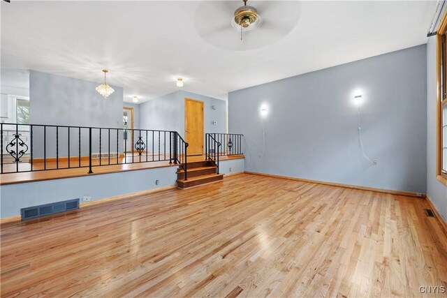 7565 Audrey Dr, Clay, NY 13212 - spare room with wood finished floors, a ceiling fan, a chandelier, stairs, and baseboards