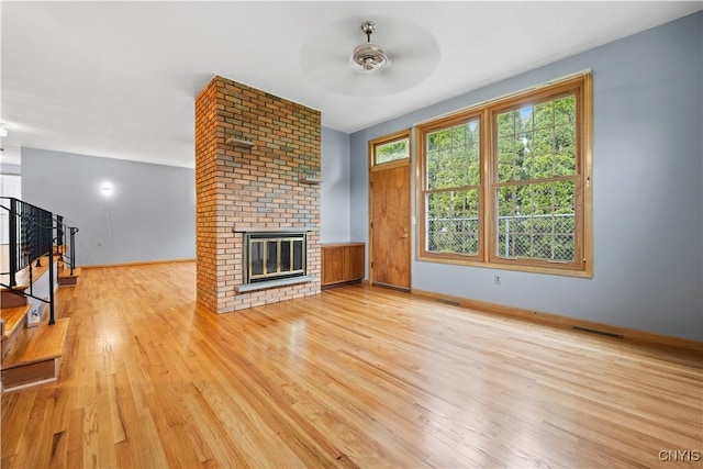 7565 Audrey Dr, Clay, NY 13212 - unfurnished living room with light wood-style floors, a ceiling fan, a fireplace, baseboards, and stairs