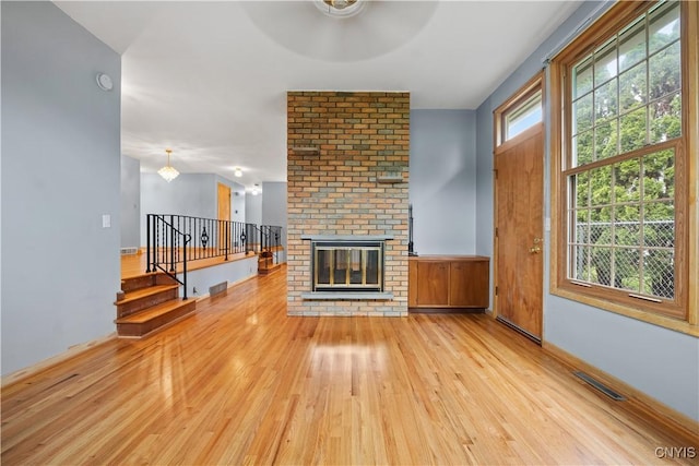7565 Audrey Dr, Clay, NY 13212 - unfurnished living room featuring light wood-style floors, a fireplace, stairs, a ceiling fan, and baseboards