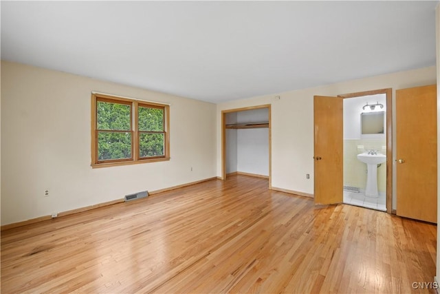 7565 Audrey Dr, Clay, NY 13212 - unfurnished bedroom with light wood finished floors, connected bathroom, a closet, a sink, and baseboards