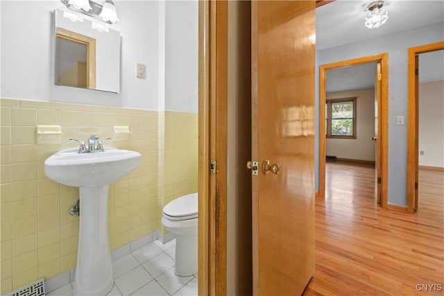 7565 Audrey Dr, Clay, NY 13212 - bathroom with tile walls, toilet, wood finished floors, a wainscoted wall, and a sink