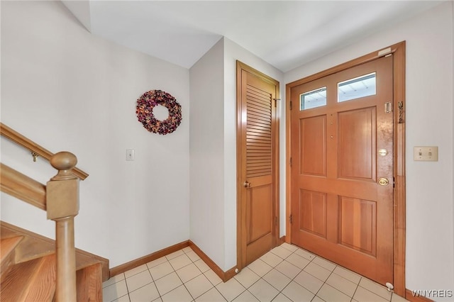 foyer featuring baseboards, stairway, and light tile patterned floors
