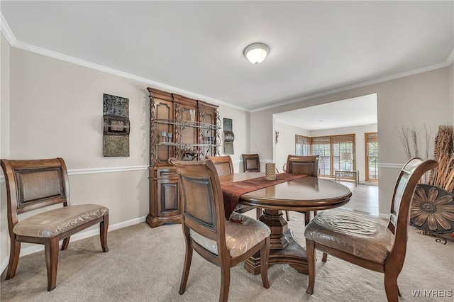 dining room with crown molding, light carpet, and baseboards