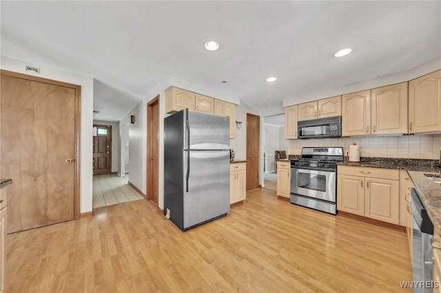 kitchen with stainless steel appliances, light brown cabinetry, light wood finished floors, tasteful backsplash, and baseboards