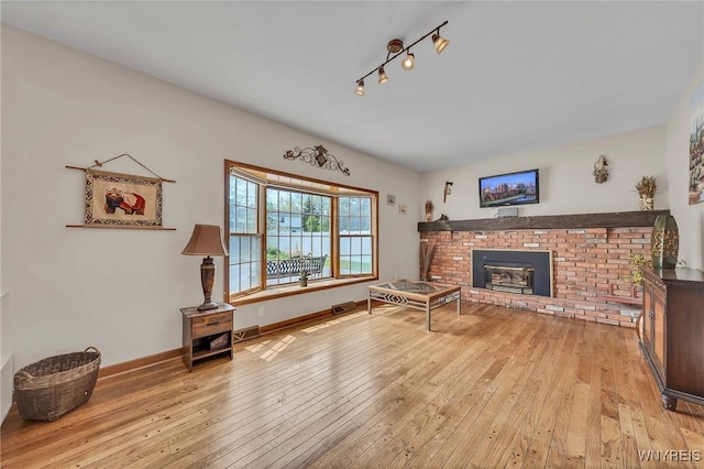 living area featuring light wood finished floors, a fireplace, and baseboards