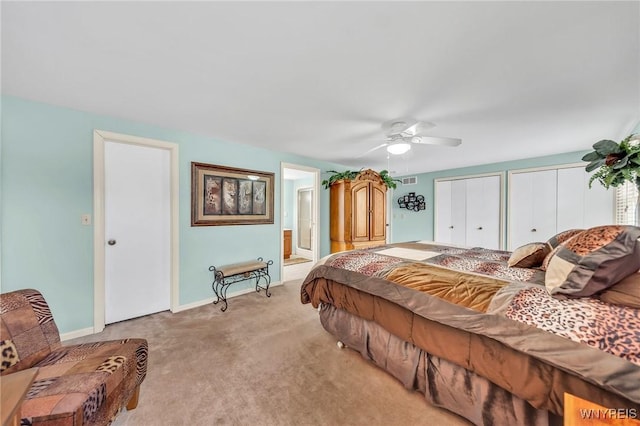 bedroom featuring multiple closets, light colored carpet, connected bathroom, baseboards, and a ceiling fan