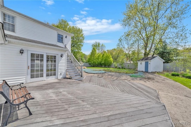 deck with a shed, a fenced backyard, stairs, and an outbuilding