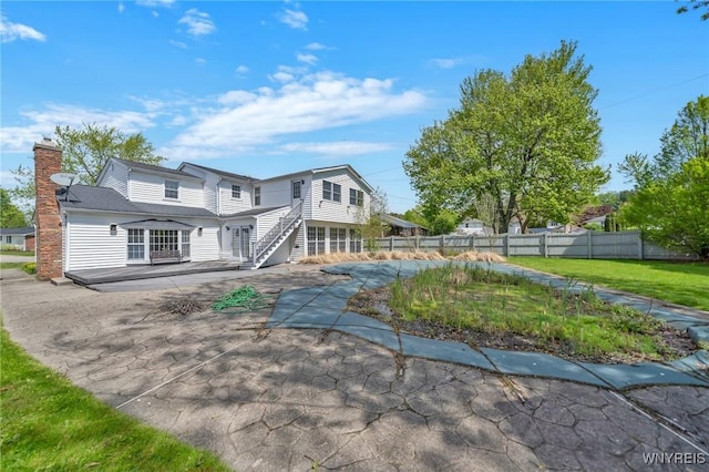 view of front of house with a chimney, a patio area, and fence