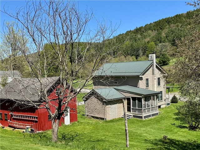 2395 State Highway 205, Laurens, NY 13810 - back of house featuring a chimney, a lawn, an outdoor structure, and a forest view