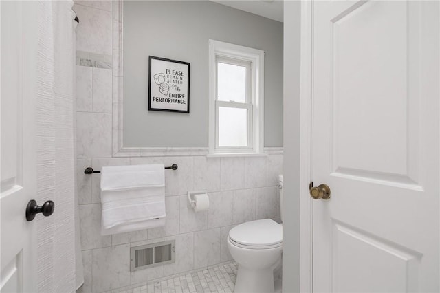 full bathroom featuring toilet, tile walls, wainscoting, and a shower with shower curtain