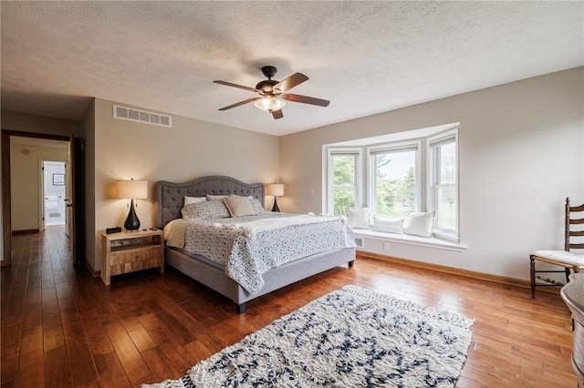 bedroom with dark wood-type flooring, baseboards, a textured ceiling, and ceiling fan