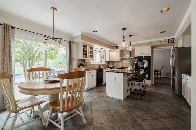 kitchen featuring black appliances, dark countertops, white cabinetry, a center island, and a kitchen bar