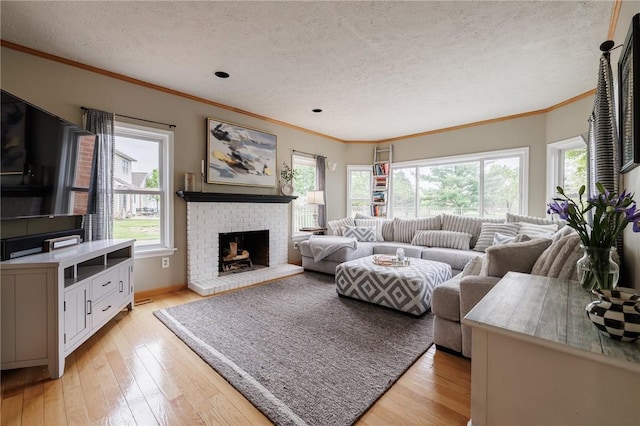 living area with a textured ceiling, crown molding, light wood-type flooring, a brick fireplace, and baseboards