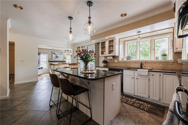 kitchen featuring healthy amount of natural light, dark countertops, a kitchen breakfast bar, crown molding, and recessed lighting