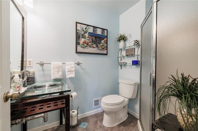 bathroom featuring a sink, toilet, a stall shower, and baseboards