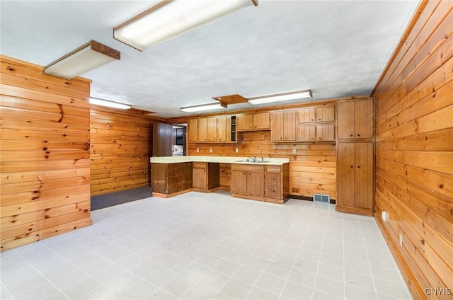 kitchen featuring wooden walls, light countertops, and a sink