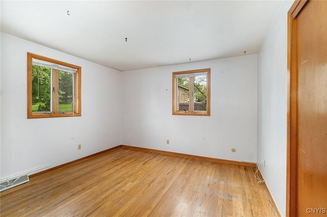 unfurnished room featuring light wood-style flooring, healthy amount of natural light, and baseboards