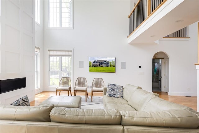 313 Wexford Ln, Horseheads, NY 14845 - living area featuring a towering ceiling, arched walkways, light wood-type flooring, plenty of natural light, and baseboards