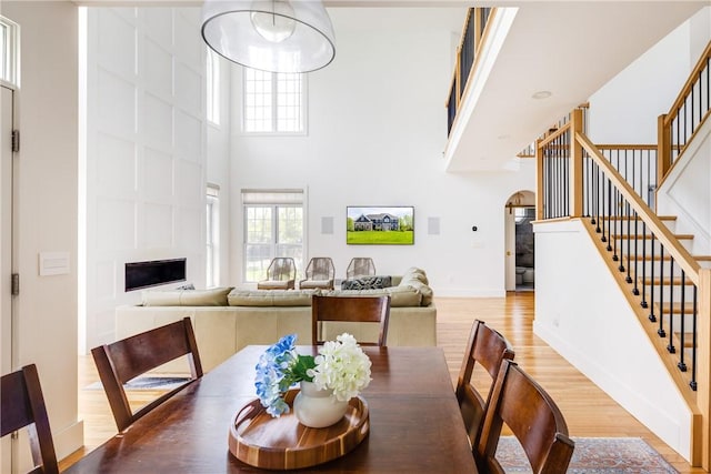 313 Wexford Ln, Horseheads, NY 14845 - dining area with light wood-style floors, a high ceiling, stairs, arched walkways, and a fireplace