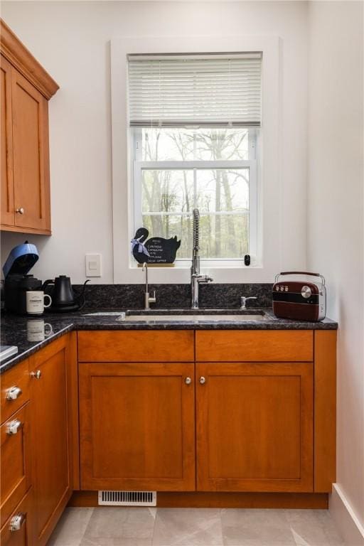 313 Wexford Ln, Horseheads, NY 14845 - kitchen with dark stone countertops, brown cabinets, a sink, and healthy amount of natural light