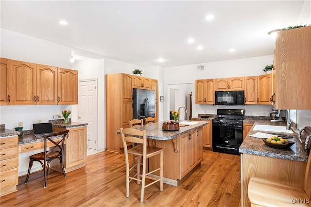 3817 Jordan Rd, Skaneateles, NY 13152 - kitchen featuring black appliances, a breakfast bar, a sink, a center island with sink, and light wood finished floors