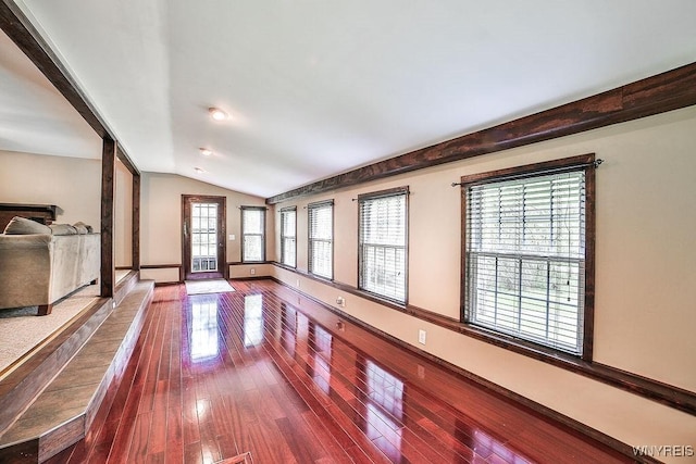 unfurnished living room with vaulted ceiling, dark wood-type flooring, and baseboards