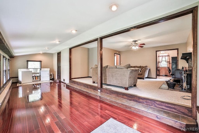 living room with a wood stove, a ceiling fan, washer and dryer, baseboards, and wood finished floors