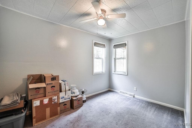 carpeted empty room featuring baseboards and a ceiling fan