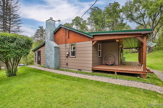 back of house with a chimney and a yard