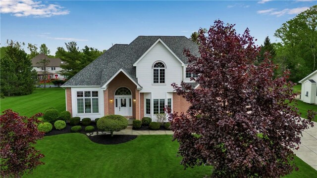 670 Raymond Dr, Lewiston, NY 14092 - traditional-style house featuring a front lawn, roof with shingles, and brick siding