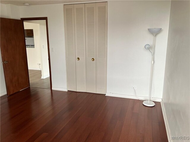 5854 Main St Unit 407, Amherst, NY 14221 - unfurnished bedroom with dark wood-style floors, baseboards, and a closet